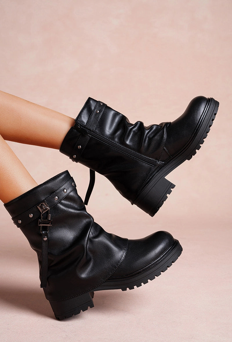 Schwarze Stiefel mit Riemen, Nieten und dicker Profilsohle.