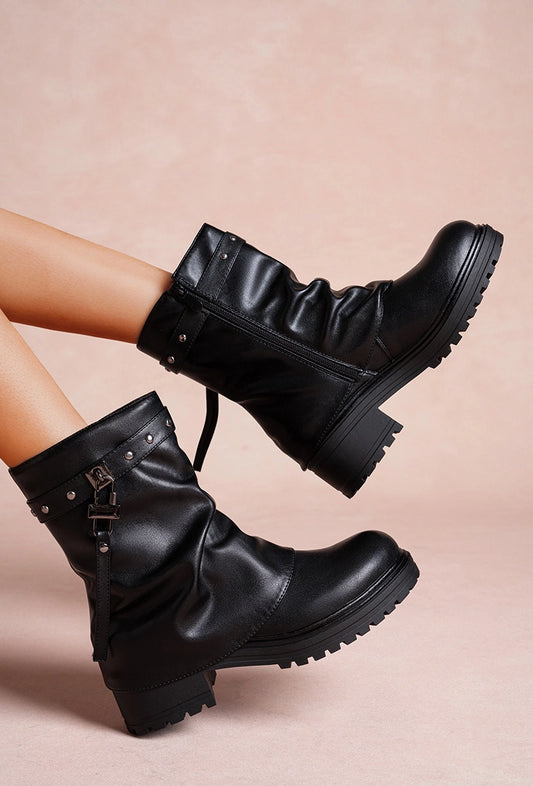 Schwarze Stiefel mit Riemen, Nieten und dicker Profilsohle.